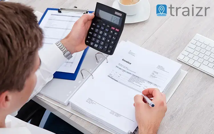 Accountant using a calculator to check invoices and paperwork with Traizr logo overlay, illustrating secure mail and parcel tracking for accountancy firms