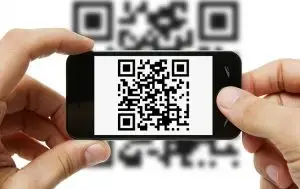 Hands holding a smartphone displaying a QR code with blurred QR background, illustrating Traizr's use of QR codes for parcel tracking