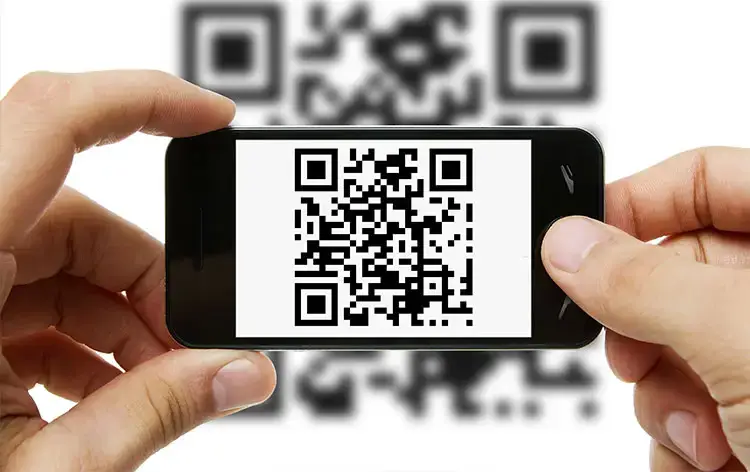 Hands holding a smartphone displaying a QR code with blurred QR background, illustrating Traizr's use of QR codes for parcel tracking